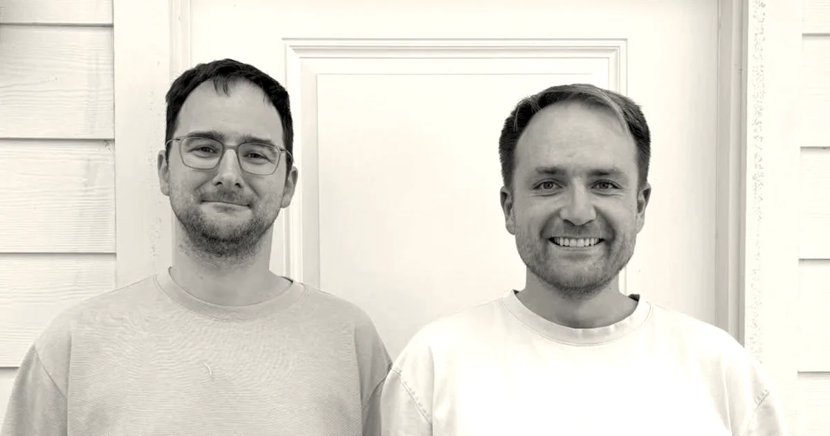 Portrait of Keenable co-founders Matthias Petri and Andrey Styskin smiling in front of a white door