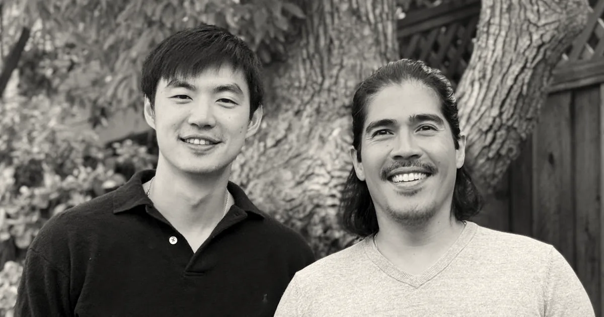 Two smiling men, the co-founders of AegisAI, standing side-by-side outdoors in front of a tree.