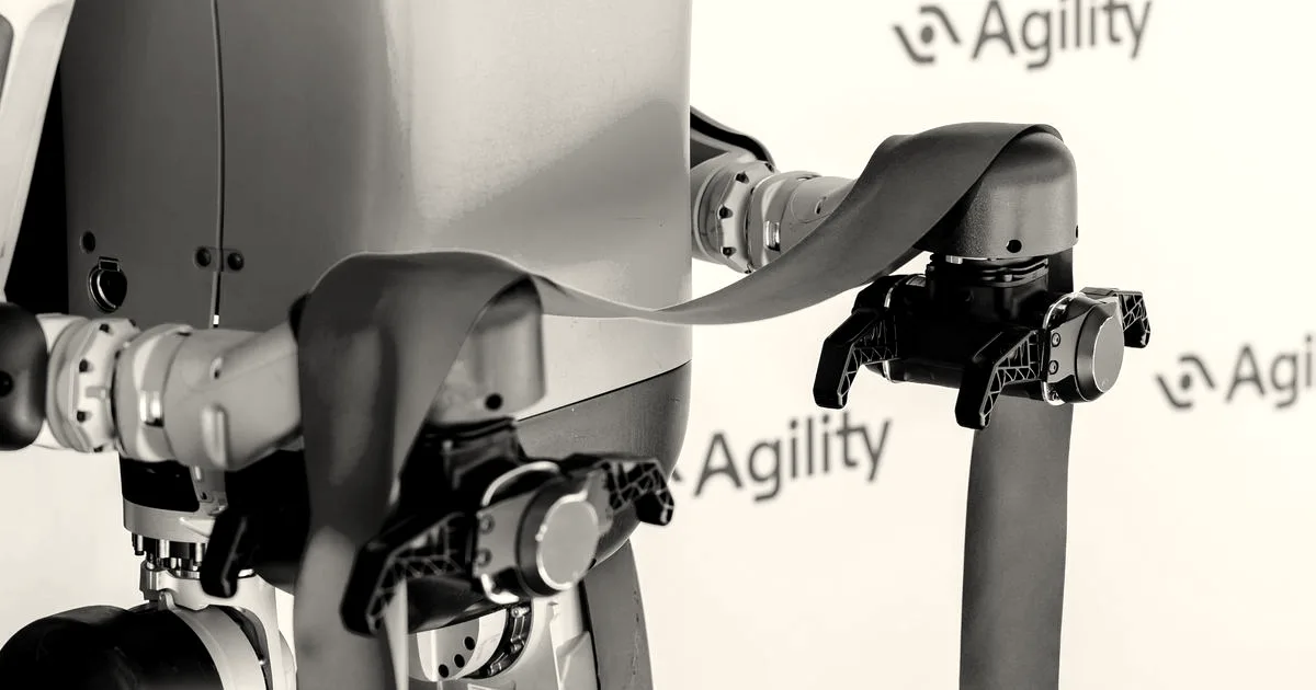 Agility Robotics Digit humanoid robot torso holding a red ribbon during an event with Agility branding in the background.