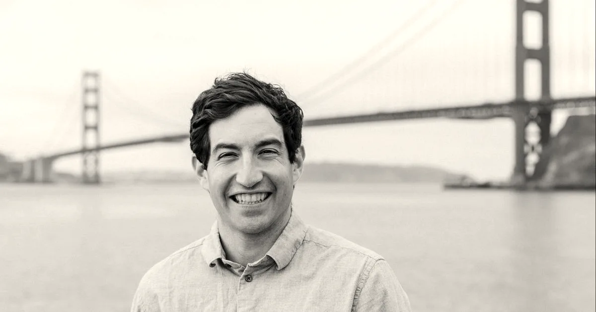 Portrait of Jacob Bank smiling outdoors with the Golden Gate Bridge visible in the background