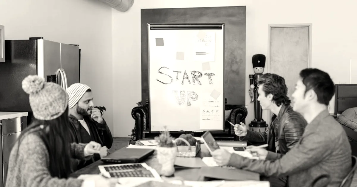 A diverse group of adults working together around a table in a bright startup office.