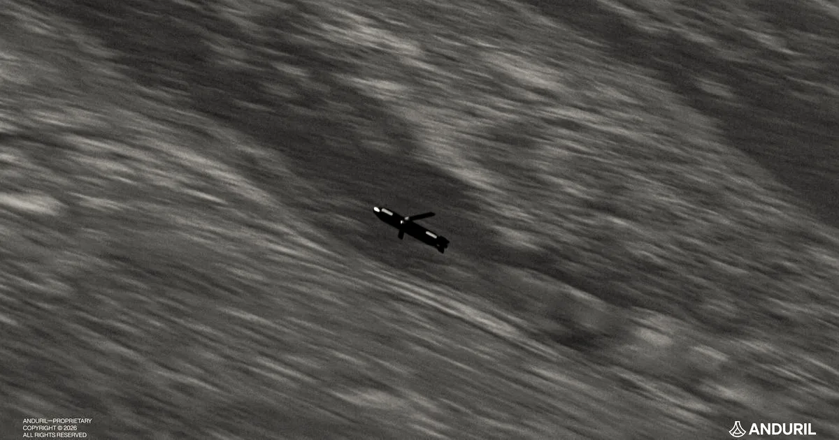 An Anduril military drone in flight against a blurred background of mountainous terrain.