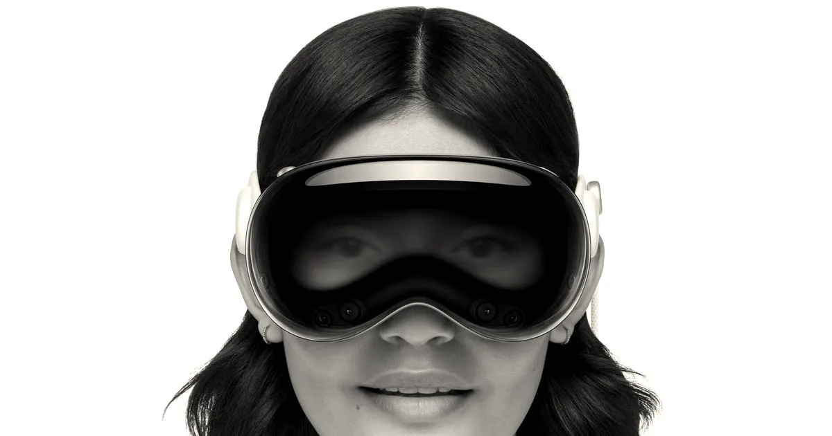 Close-up of a smiling woman wearing an Apple Vision Pro headset against a white background.