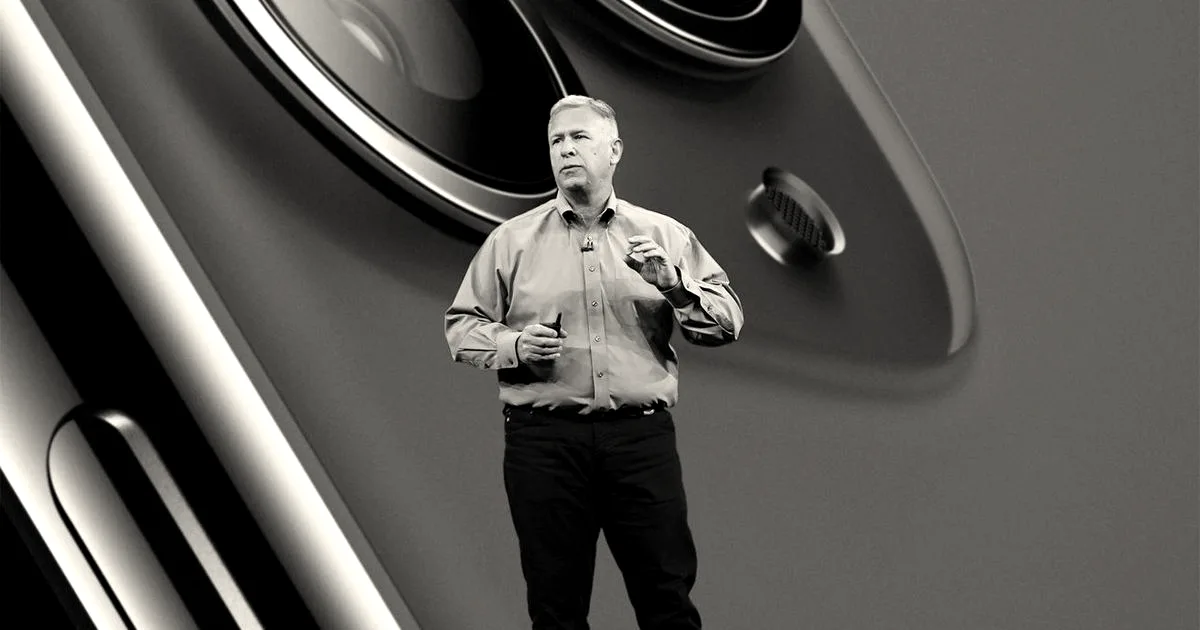Phil Schiller speaking on an Apple stage in front of a giant image of iPhone camera lenses.
