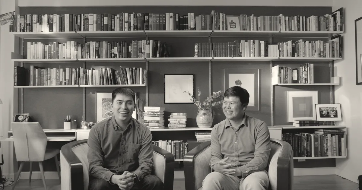Pangram founders Max Spero and Bradley Emi sitting in armchairs in front of a blue bookshelf.