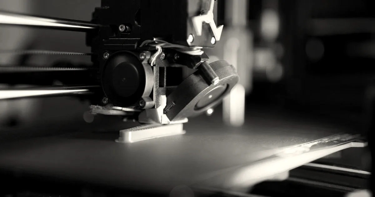 Close-up of a 3D printer in action with neon lighting, showcasing technology in prototyping.