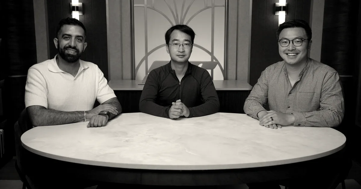 Three co-founders of Safeworld sitting together smiling at a round marble table in an office setting.