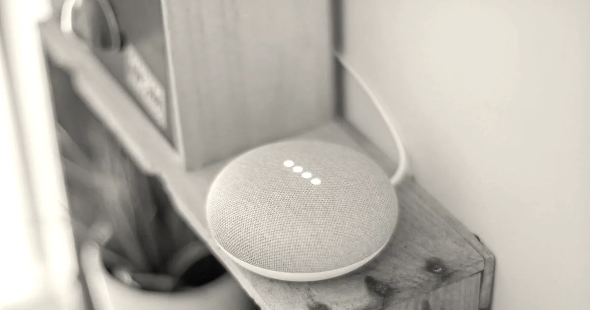 A Google Home Mini smart speaker on a wooden shelf, blending technology with home decor.