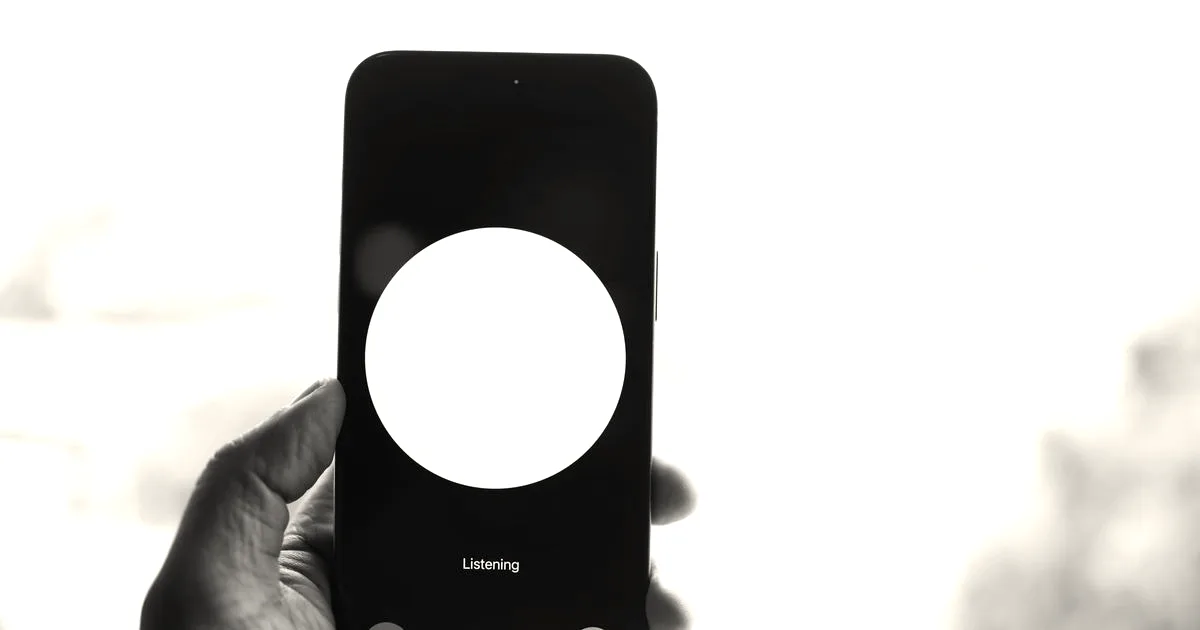A hand holding a smartphone showing a black screen with a large white circle and text indicating voice interaction.