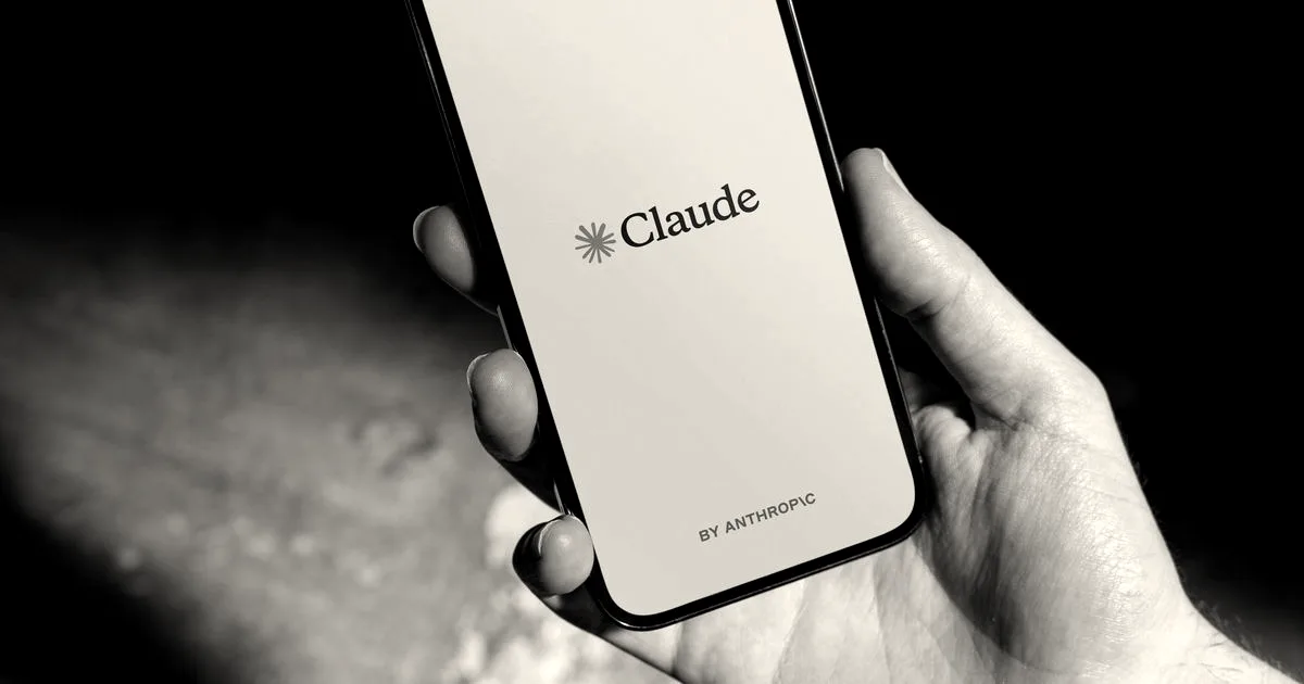 A hand holding a smartphone displaying the Claude AI application splash screen with the Anthropic logo.