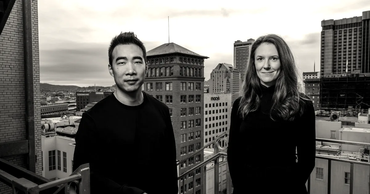 Two people, a man and a woman, standing on a balcony overlooking a city skyline.