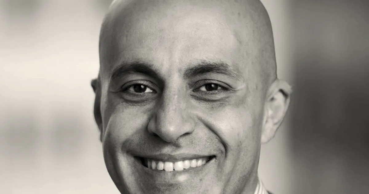 Close-up portrait of Databricks CEO Ali Ghodsi smiling against an office background