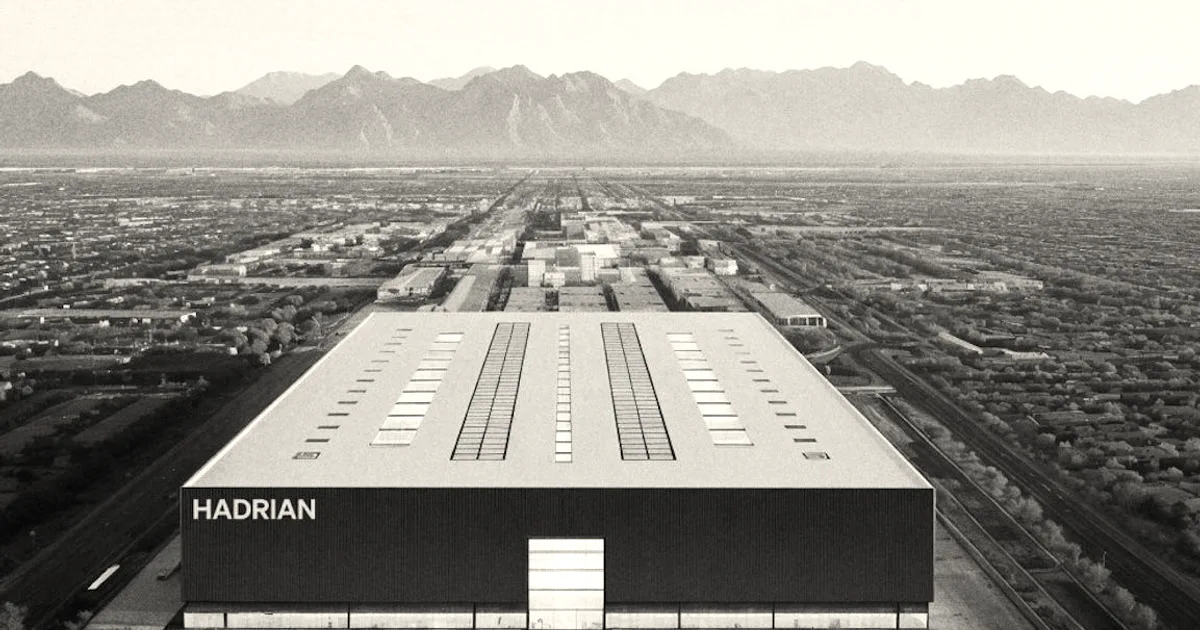 Architectural rendering of a large blue and white Hadrian manufacturing facility in a desert landscape.
