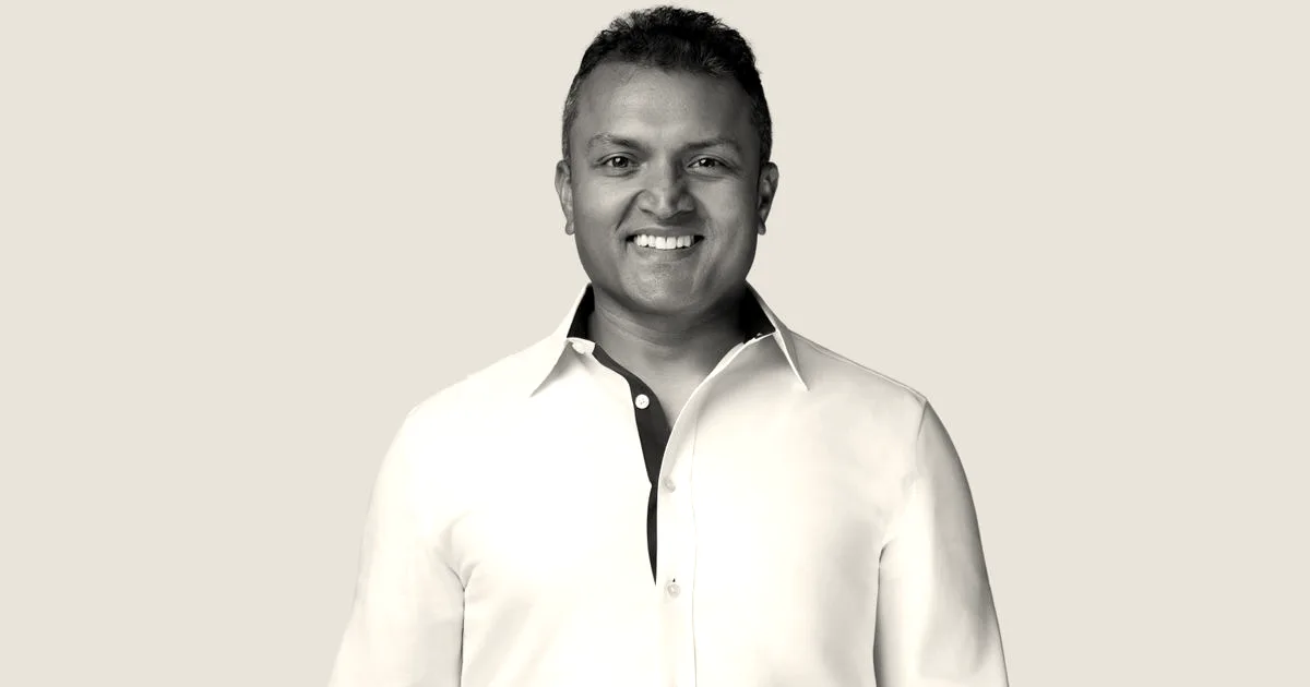 Portrait of Adit Singh smiling against a plain grey background, wearing a white collared shirt.