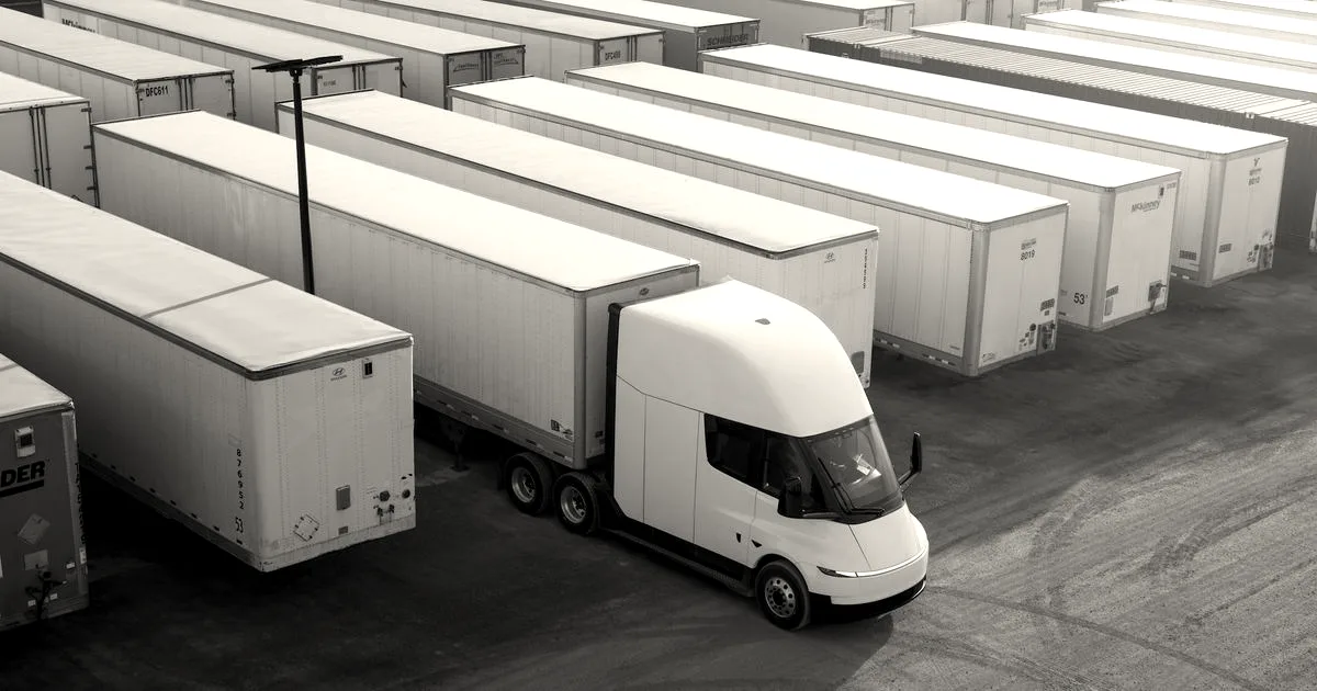 A white Tesla Semi electric truck parked among rows of semi-trailers in a parking lot