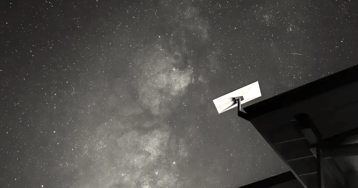 A Starlink satellite terminal mounted on a building roof facing a starry night sky.
