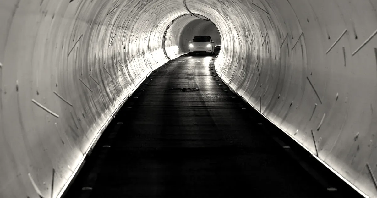A Tesla car driving inside The Boring Company's illuminated underground tunnel in Las Vegas.