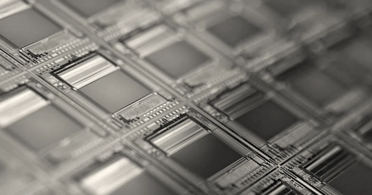 Close-up macro view of a silicon wafer displaying iridescent rectangular semiconductor microchips.