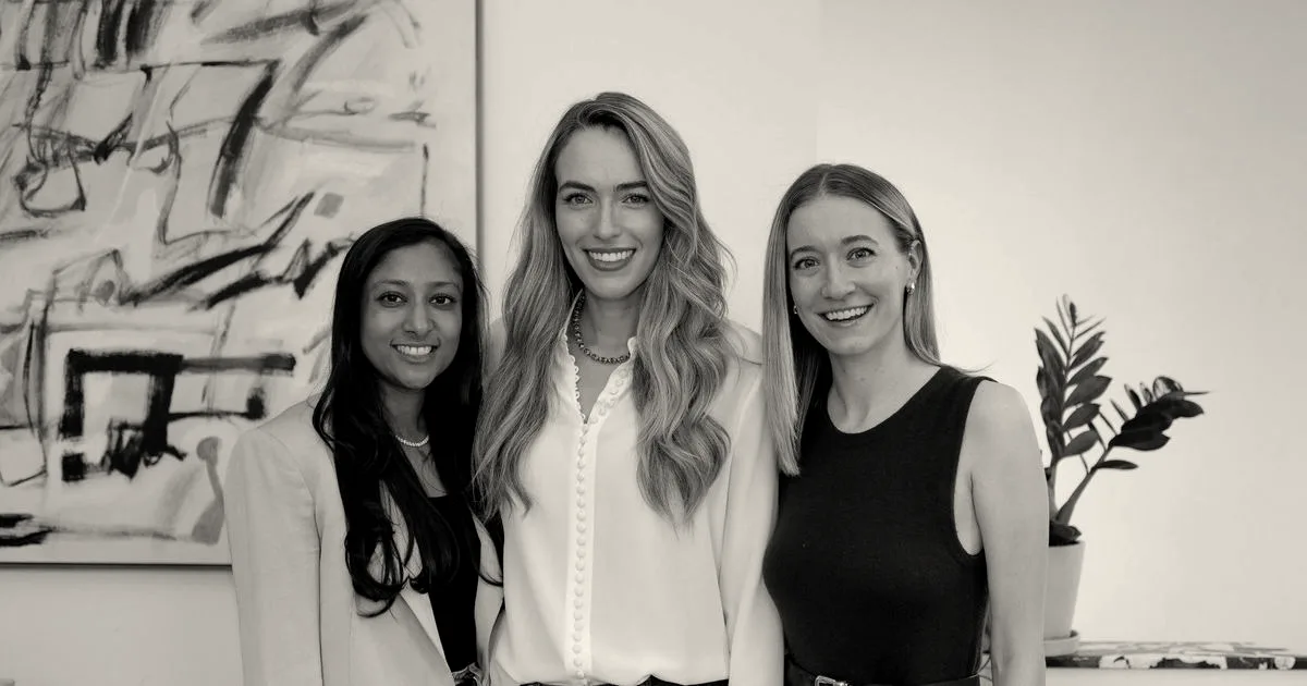 Three smiling female founders of Evvy posing together indoors in front of an abstract painting.