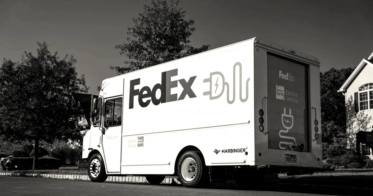 A white FedEx electric delivery truck featuring green battery graphics parked on a suburban street.