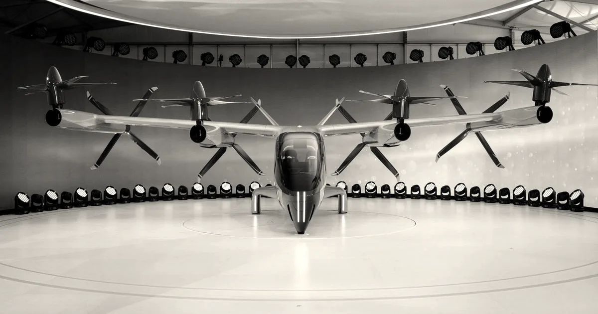Front view of a futuristic electric vehicle with propellers displayed indoors.