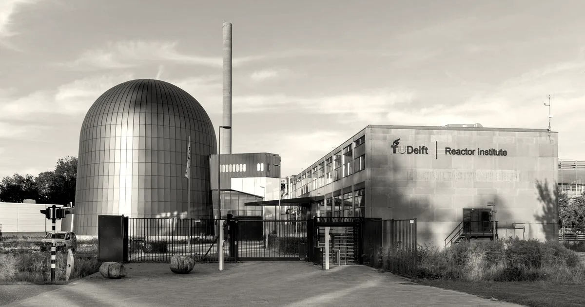 Exterior view of the TU Delft Reactor Institute building and dome under a clear blue sky
