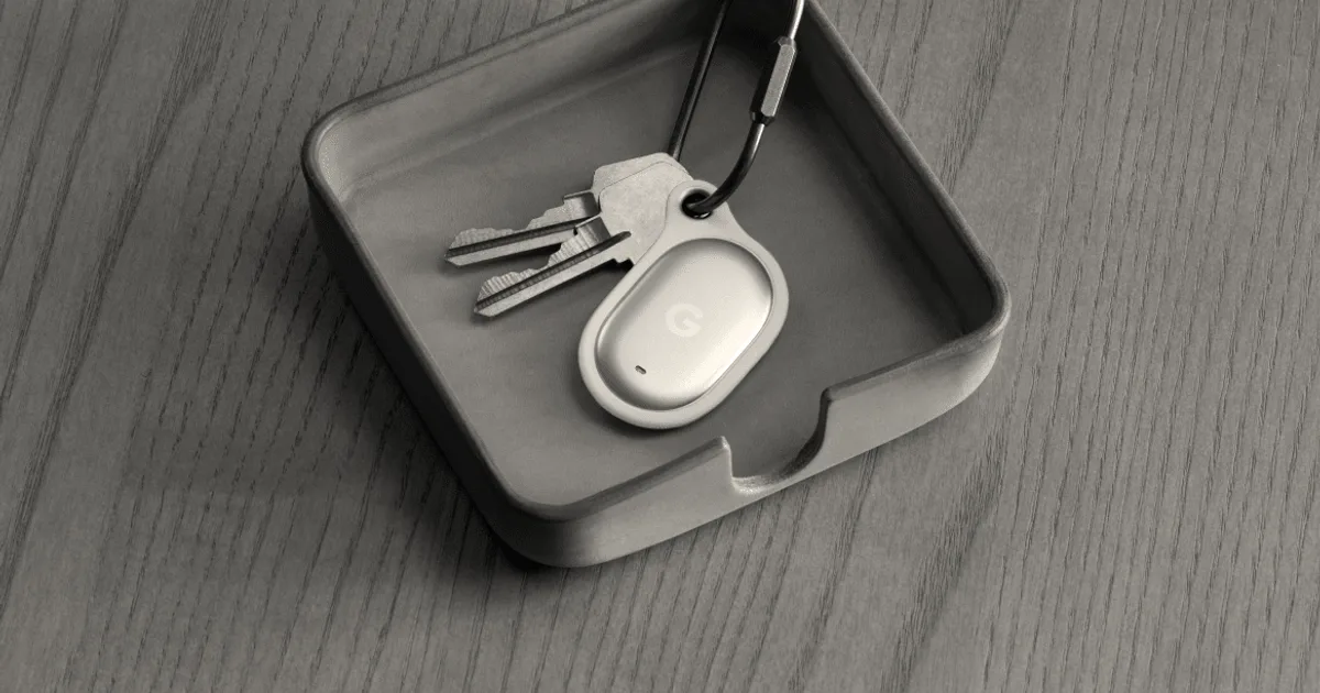 A grey Google Pixel Tag connected to keys sitting inside a small terracotta tray.