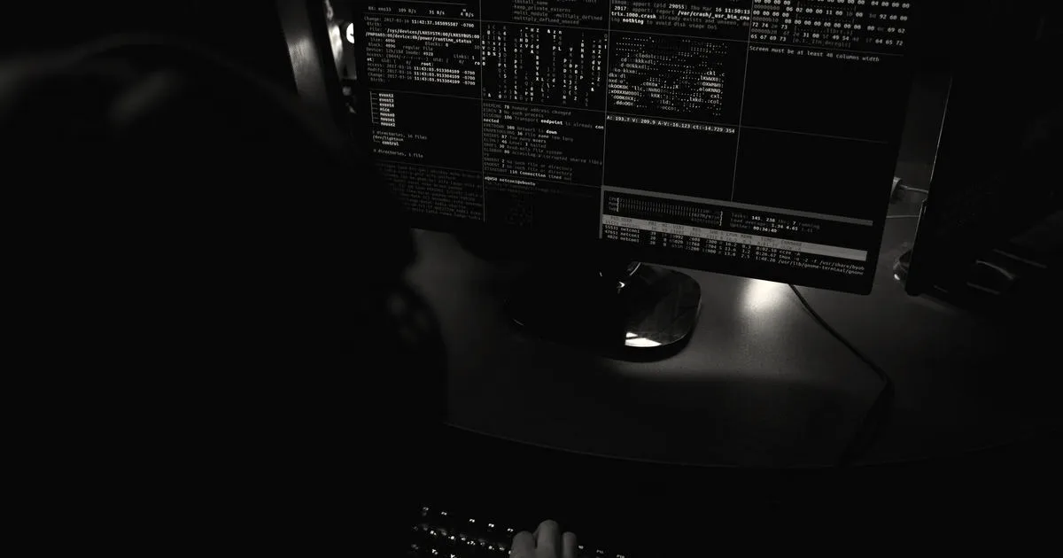 Dark room setup with code displayed on PC monitors highlighting cybersecurity themes.