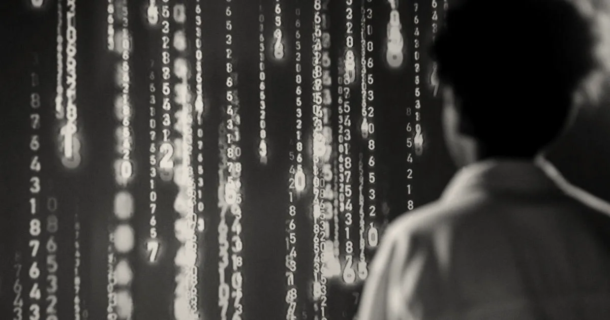 A person looking at vertical streams of glowing digits cascading down a screen in a dark room