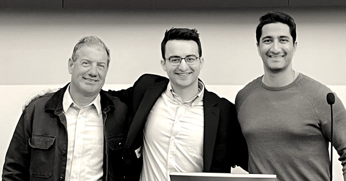 Three smiling men, the founders and partners of Blue Voice, standing side by side indoors.
