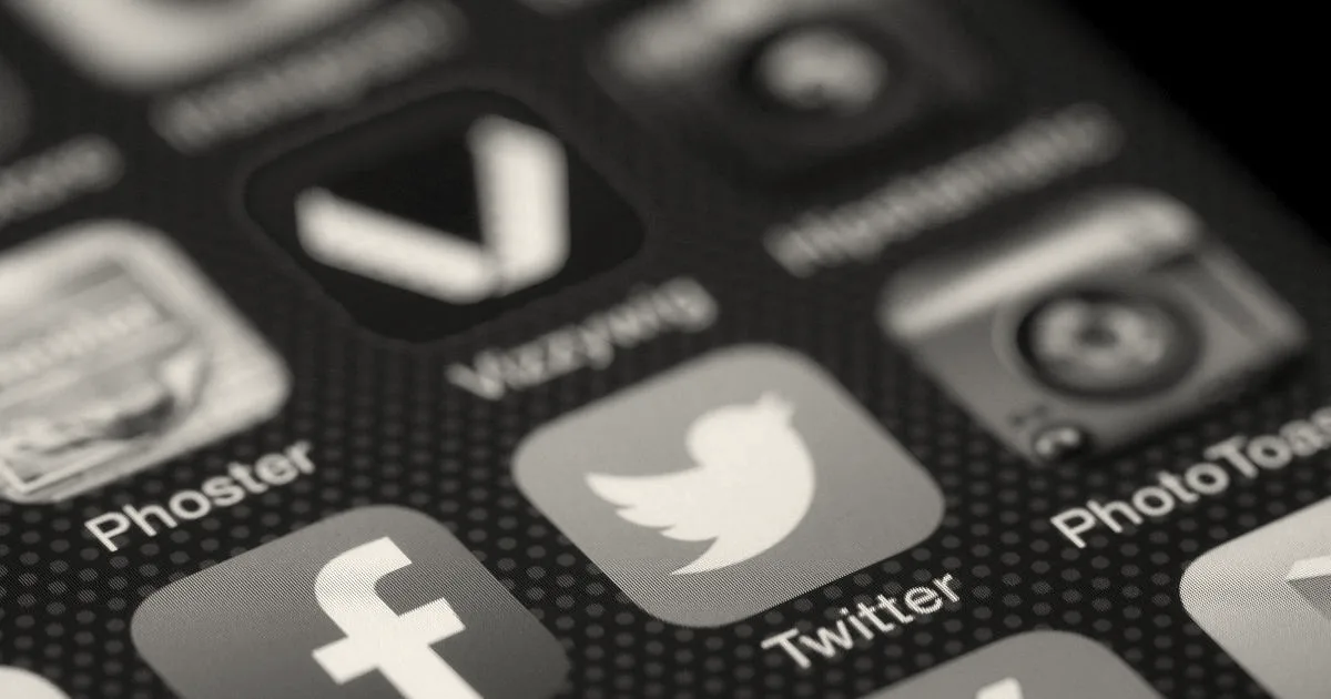 Close-up view of a smartphone display highlighting social media app icons including Twitter and Facebook