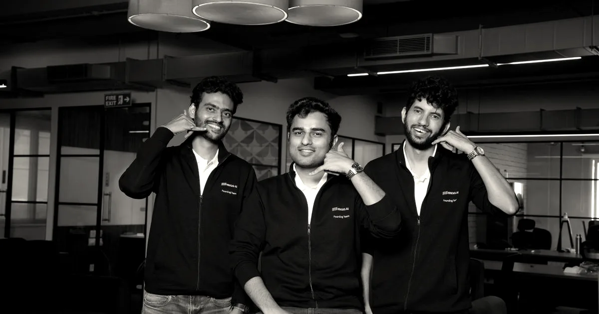 Three co-founders of Ringg smiling and gesturing phone shapes with their hands in an office setting.