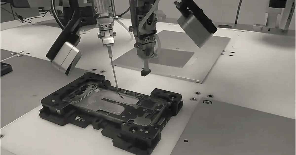Robotic precision tools operating over a smartphone chassis held on a manufacturing assembly jig.