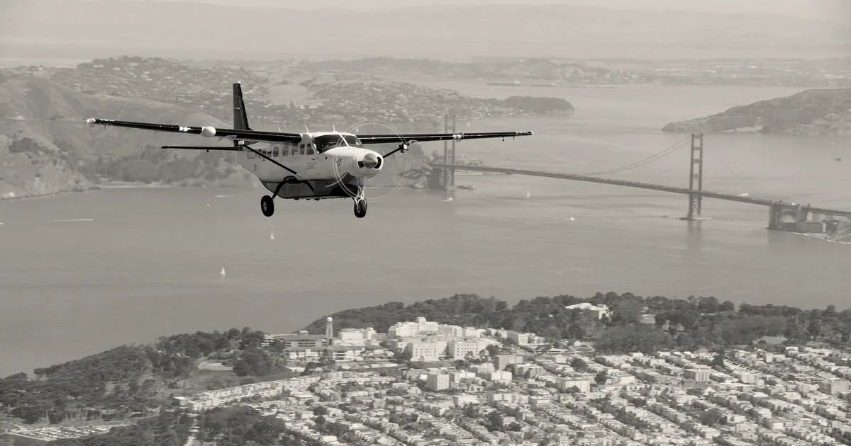 A Joby Aviation autonomous test plane flying over San Francisco with the Golden Gate Bridge behind it.