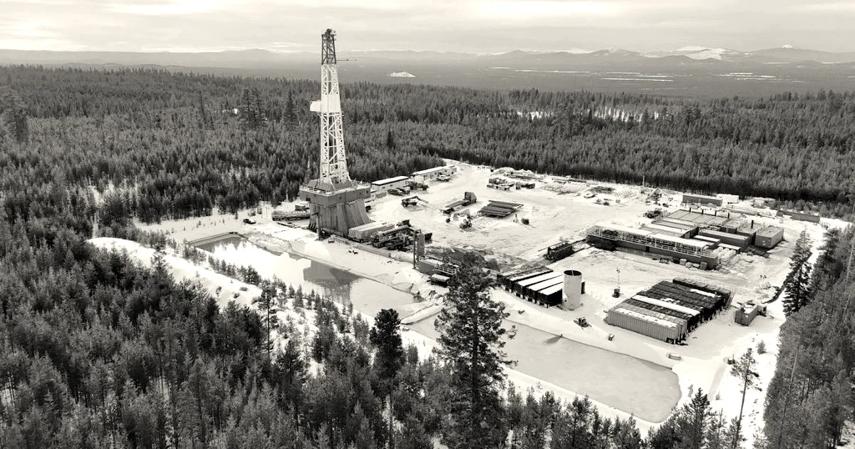 Aerial view of a Mazama Energy geothermal drilling rig and site surrounded by evergreen forest in snow-dusted Oregon.