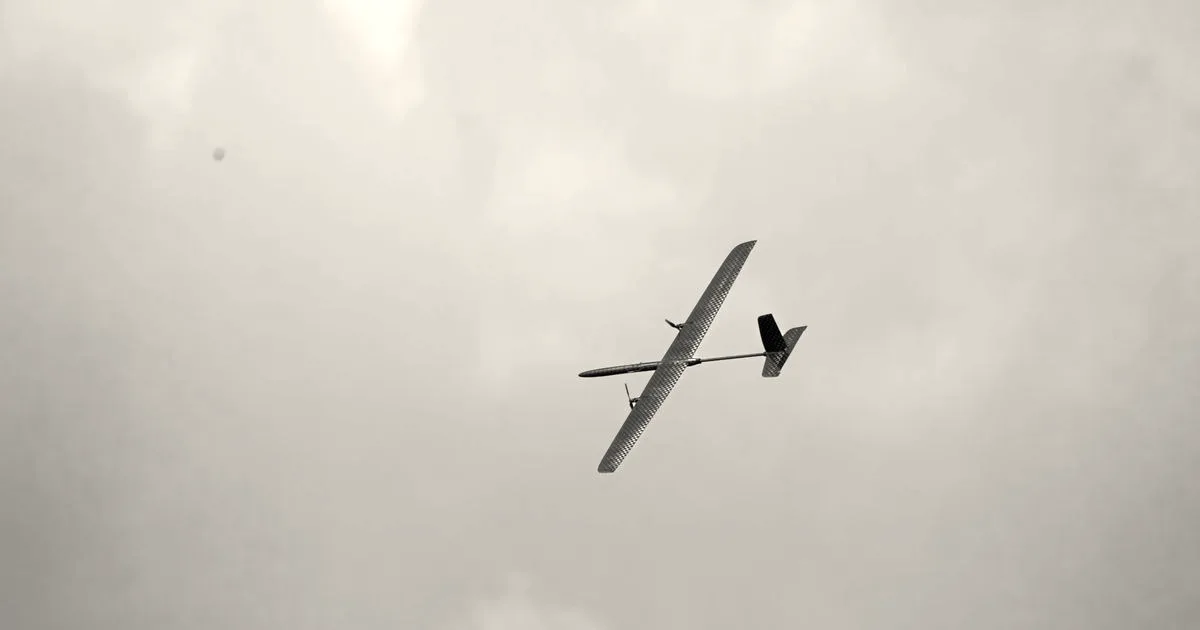 An Alteon autonomous long-endurance aircraft soaring high in a light blue sky with faint clouds.