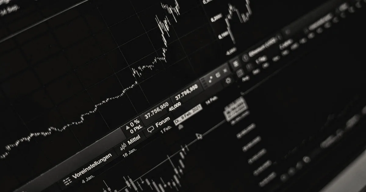 Close-up of financial stock market candlestick charts and data displayed on a dark computer monitor