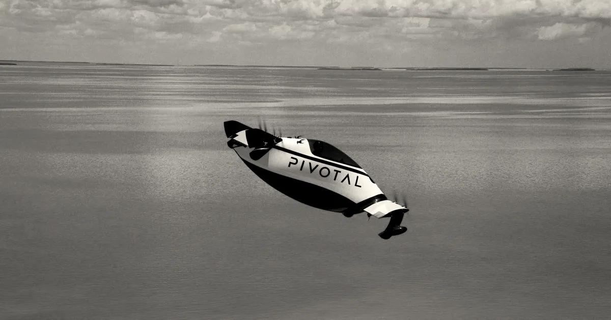 A white and black Pivotal Helix personal aircraft flying over turquoise open water.