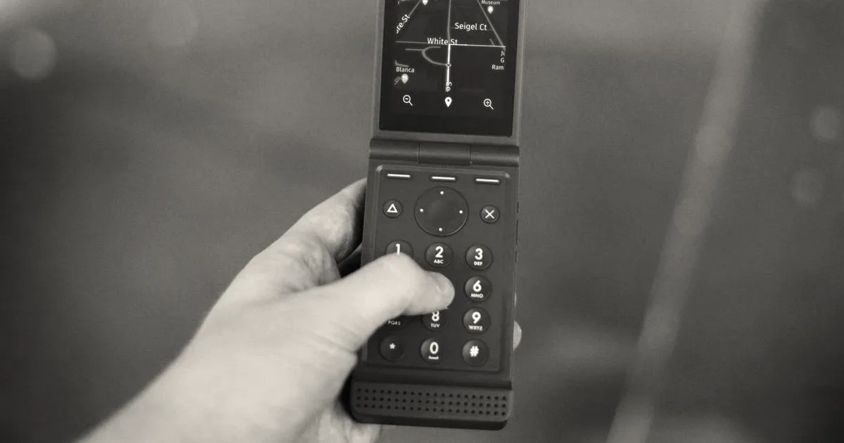 A person holding a bright red Light flip phone showing a map interface on its screen.