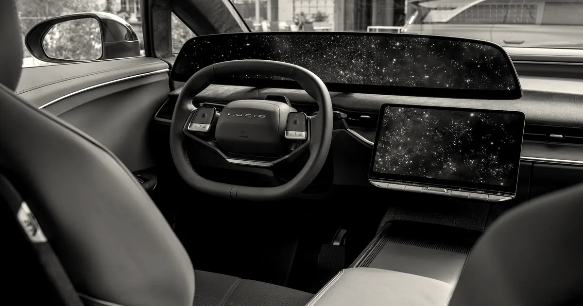 Interior of a Lucid electric vehicle showing the steering wheel, wide curved digital dashboard, and center console screen