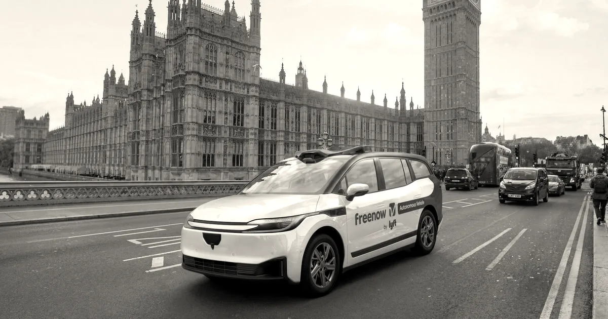 A white autonomous vehicle branded with Freenow by Lyft driving on a street in London near Big Ben.