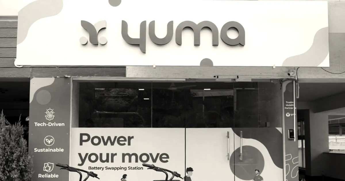 Exterior of a Yuma Energy battery swapping station with branded electric two-wheelers parked in front.