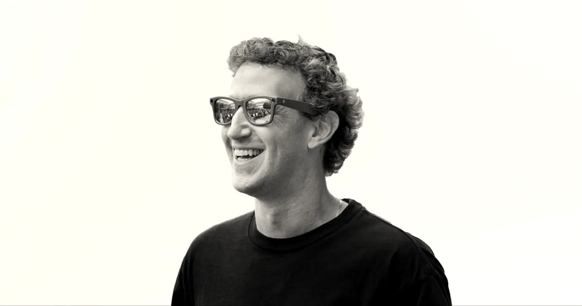 Mark Zuckerberg smiling while wearing blue sunglasses outdoors against a light blue background.