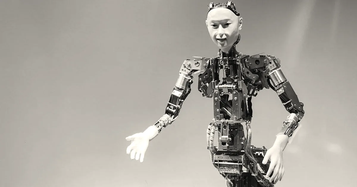 An advanced humanoid robot with robotic torso and arms gesturing against a neutral background