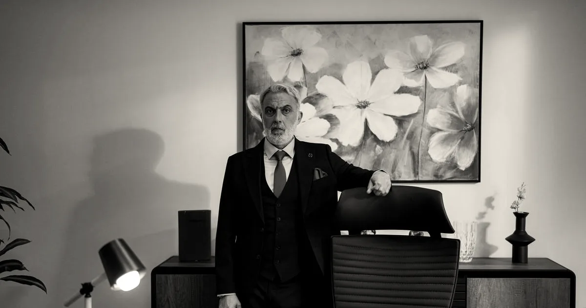 Distinguished mature business professional standing confidently in a modern office near an executive desk.