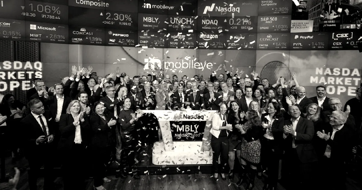 A large crowd of people celebrating on stage at the Nasdaq MarketSite with Mobileye branding on the screens.