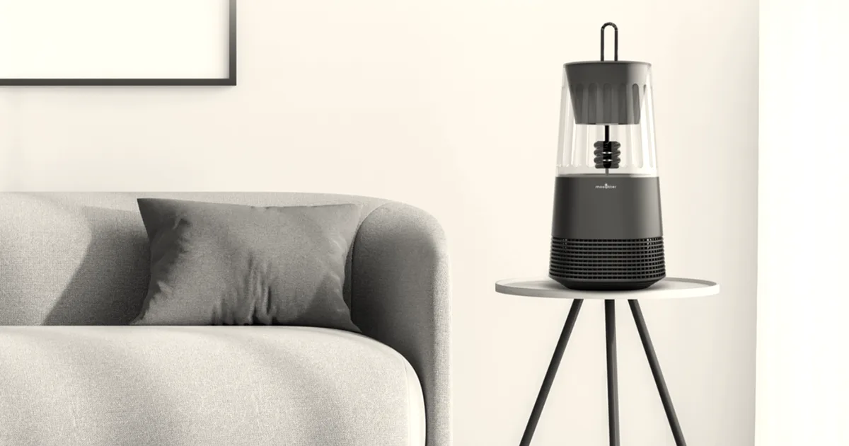 A sleek dark green Mosqitter mosquito trap device resting on a small round side table next to a sofa.
