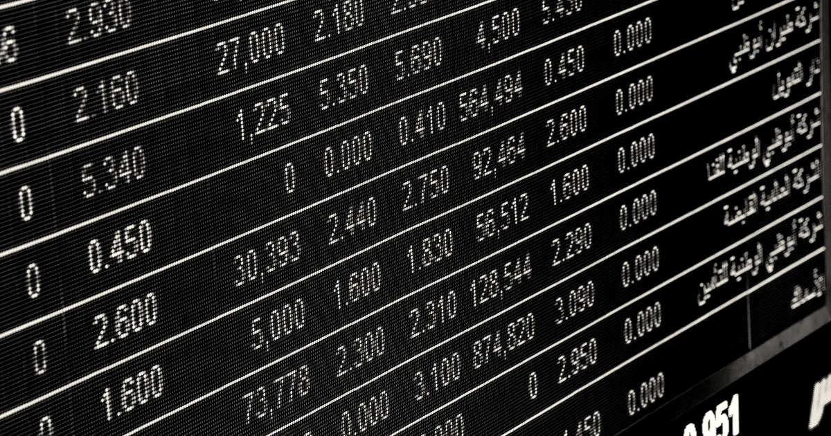Close-up view of a digital stock market ticker board displaying financial numbers and market data