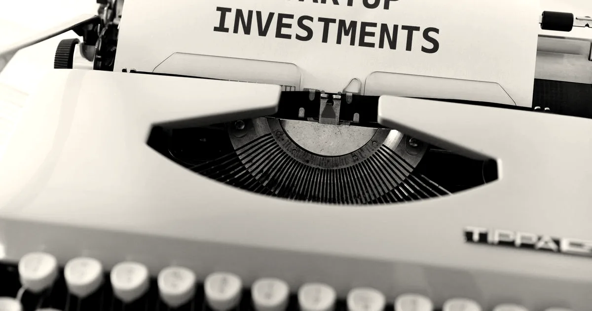 A vintage typewriter with a paper that reads 'Startup Investments' inserted into the roller.