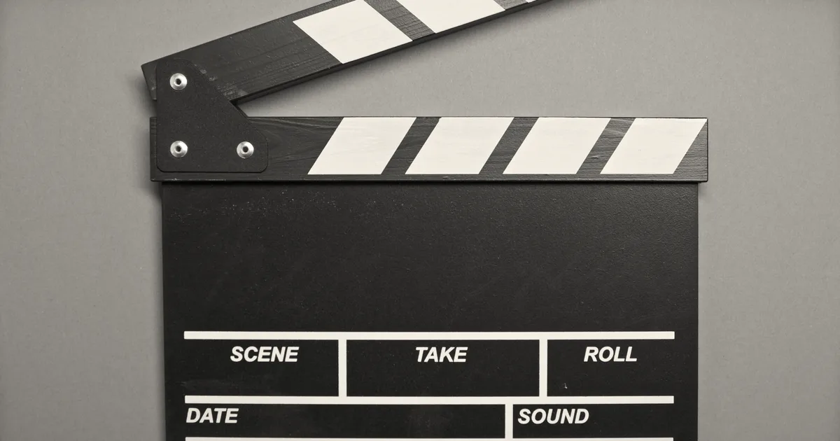 A classic film clapperboard on a green surface, essential for movie scenes.